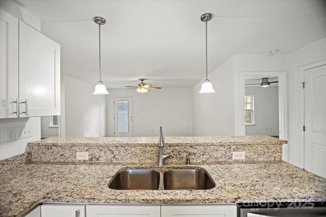 kitchen featuring hanging light fixtures, white cabinetry, sink, and light stone counters