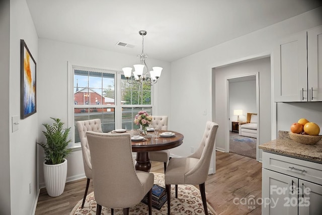 dining area with light hardwood / wood-style floors and a chandelier