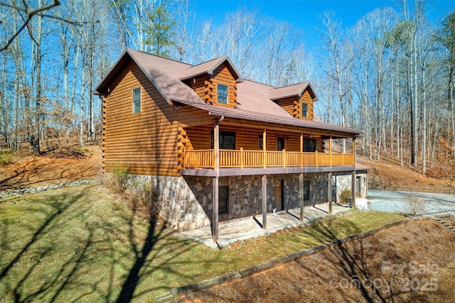 exterior space featuring log exterior, stone siding, a lawn, and a patio area