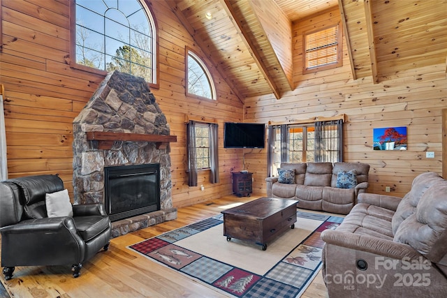 living area featuring light wood finished floors, wood walls, a fireplace, and wood ceiling