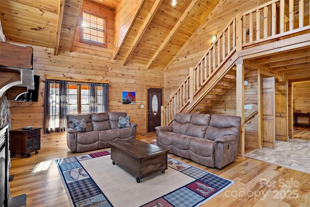 living area with light wood finished floors, wood ceiling, wooden walls, high vaulted ceiling, and stairs