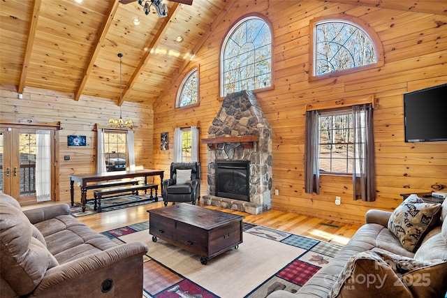 living area featuring a stone fireplace, light wood-style flooring, wood walls, wood ceiling, and beamed ceiling