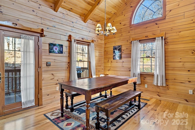 dining area with a notable chandelier, wood walls, and light wood finished floors