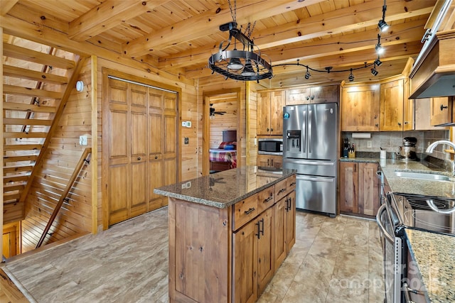 kitchen featuring stainless steel appliances, a center island, decorative light fixtures, and dark stone counters