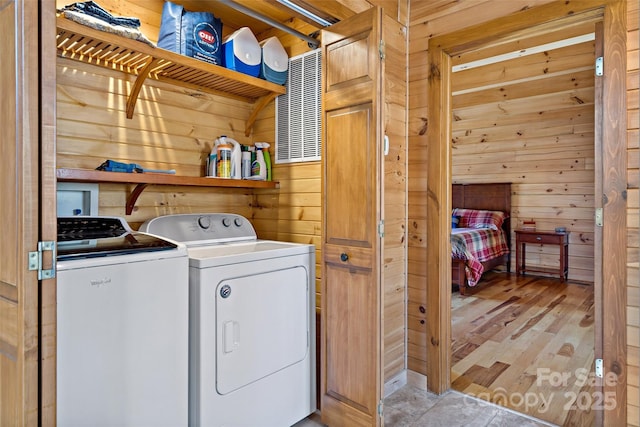 laundry room featuring laundry area, light wood-style floors, washer and dryer, and wooden walls