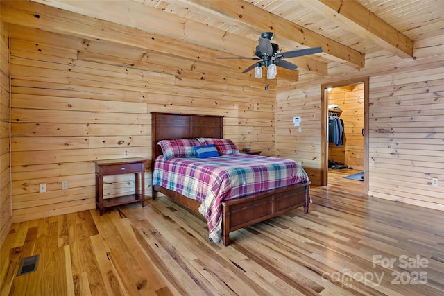 bedroom featuring light wood-style flooring, wooden walls, wood ceiling, visible vents, and beamed ceiling