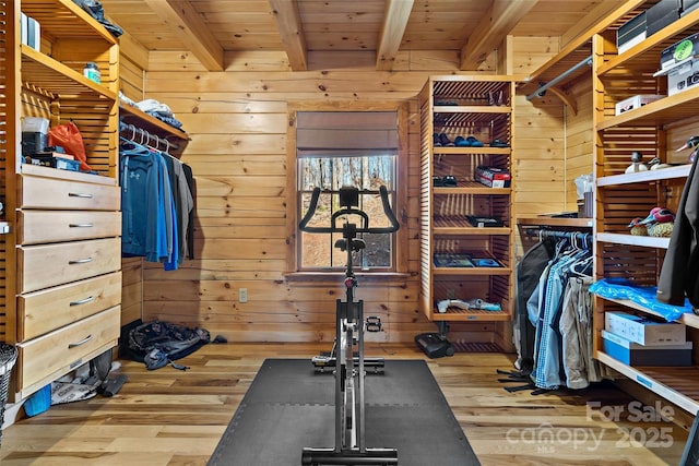 exercise room with wood ceiling, wood walls, and light wood-style flooring