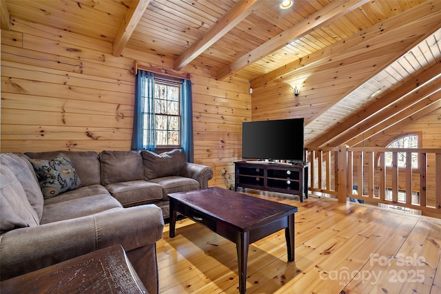 living room featuring lofted ceiling with beams, light wood finished floors, wood ceiling, and wooden walls