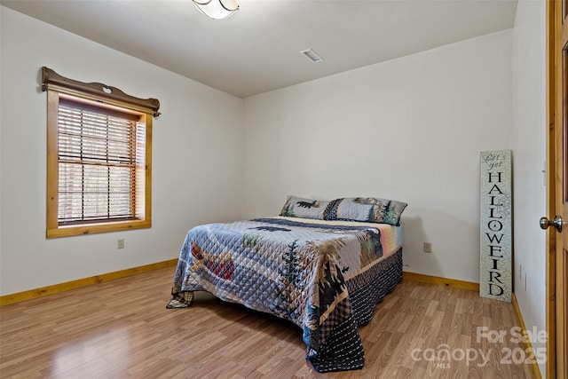 bedroom with visible vents, baseboards, and wood finished floors