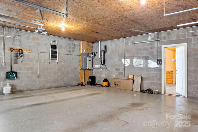 basement with a garage, concrete block wall, and electric panel