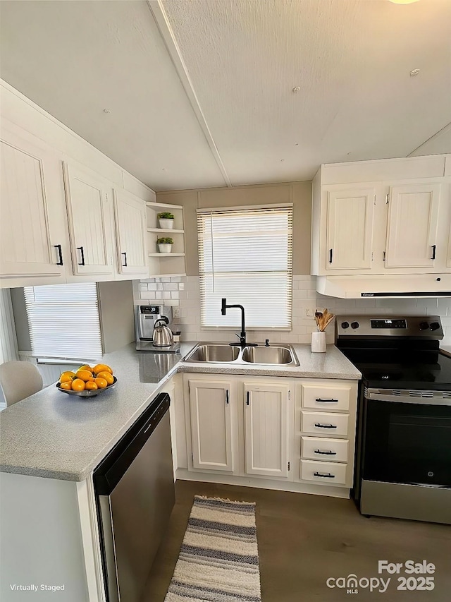 kitchen featuring a sink, light countertops, appliances with stainless steel finishes, decorative backsplash, and open shelves