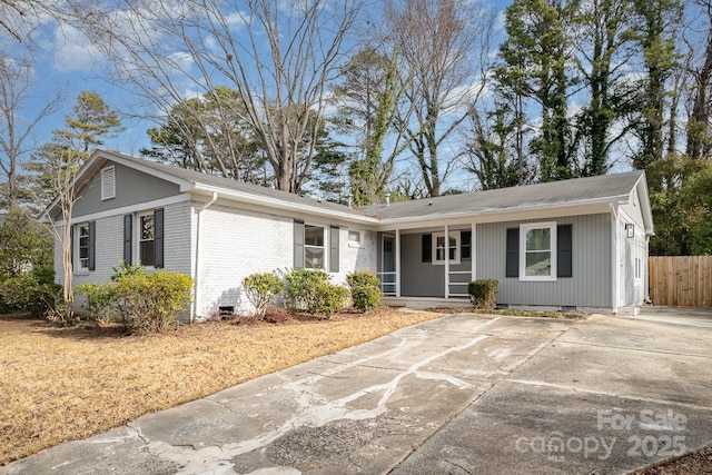 ranch-style house with covered porch, brick siding, crawl space, and fence