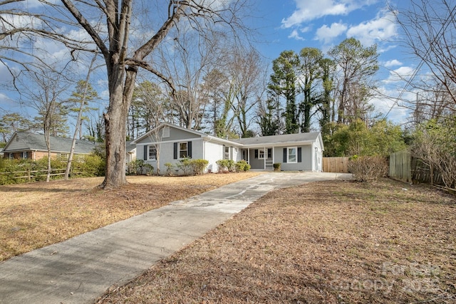 ranch-style house featuring driveway and fence