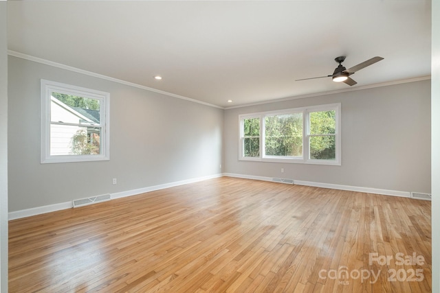 empty room featuring ornamental molding, light wood-style flooring, visible vents, and baseboards