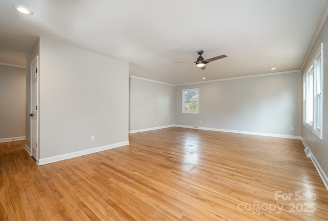 spare room with crown molding, light wood-type flooring, and baseboards