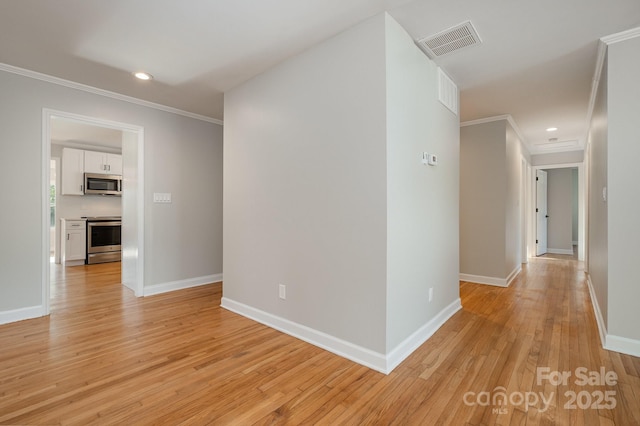 hallway featuring light wood-style floors, visible vents, ornamental molding, and baseboards