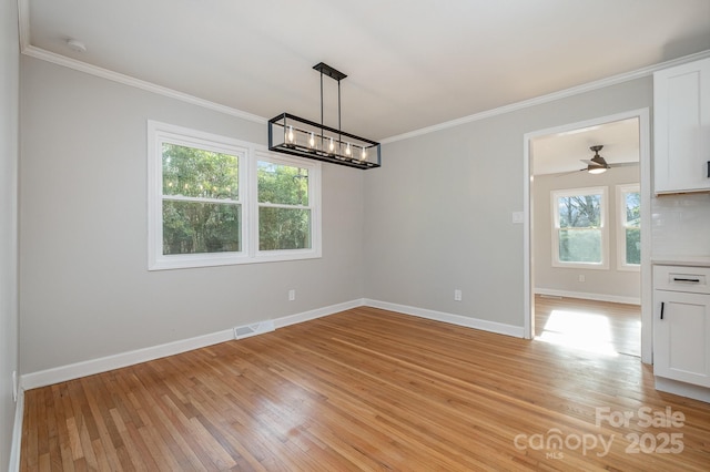 unfurnished dining area featuring ornamental molding, a notable chandelier, and light hardwood / wood-style flooring