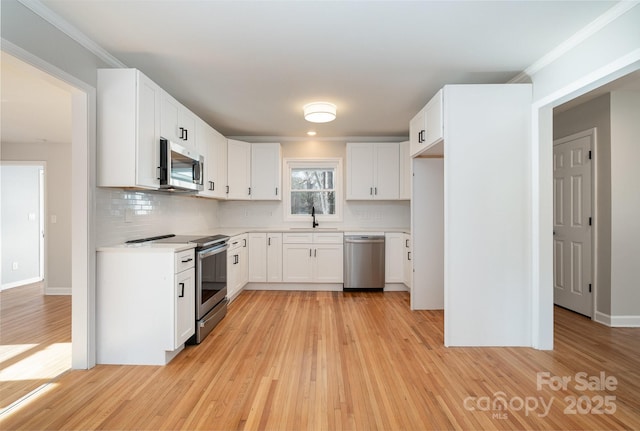 kitchen with white cabinetry, stainless steel appliances, sink, and light hardwood / wood-style flooring