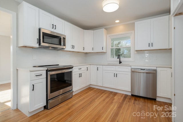 kitchen featuring light wood-style floors, stainless steel appliances, a sink, and light countertops