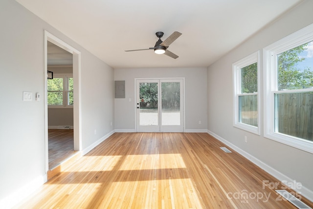 empty room with electric panel, ceiling fan, and light hardwood / wood-style flooring