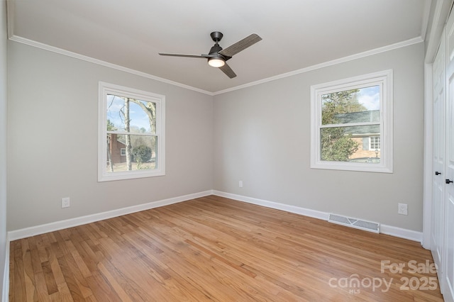 spare room with light wood-style floors, baseboards, visible vents, and crown molding