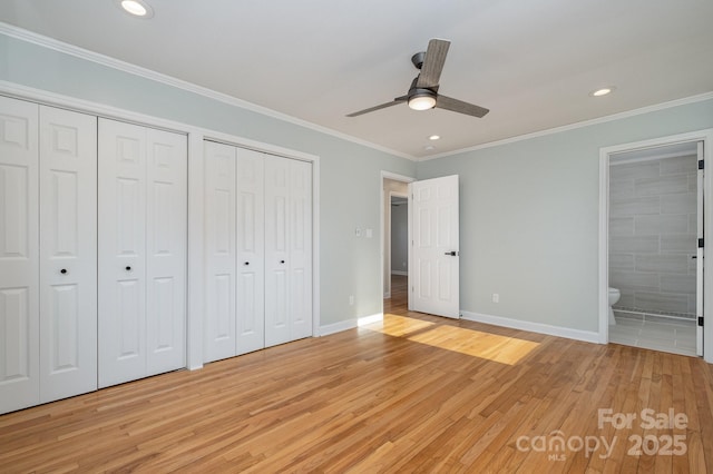 unfurnished bedroom with crown molding, baseboards, light wood-style flooring, and multiple closets