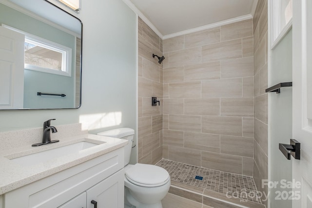 full bathroom featuring ornamental molding, tiled shower, vanity, and toilet