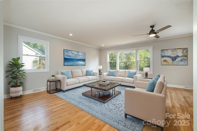 living room with visible vents, crown molding, baseboards, and wood finished floors