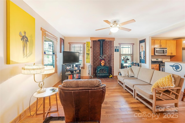 14 Drake St, Asheville, NC 28806 - living room with a wood stove, a ceiling fan, light wood-style flooring, and baseboards