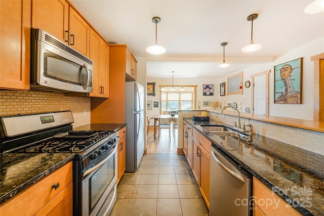 14 Drake St, Asheville, NC 28806 - kitchen featuring appliances with stainless steel finishes, a sink, backsplash, brown cabinets, and hanging light fixtures