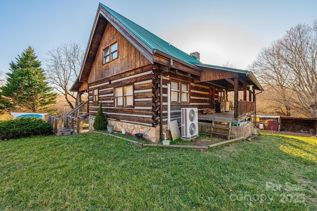 view of home's exterior with a chimney, metal roof, log exterior, and a yard