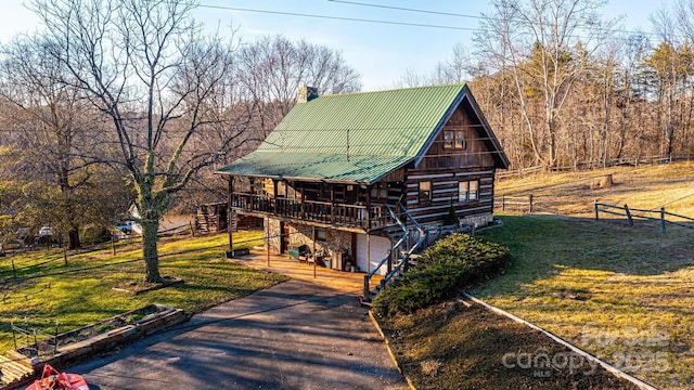 cabin with metal roof, a front lawn, fence, and driveway