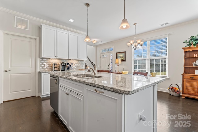 kitchen with sink, decorative light fixtures, white cabinets, and a center island with sink