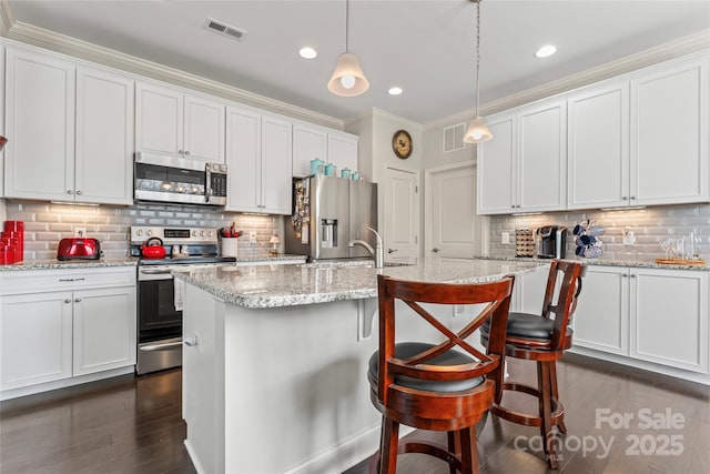 kitchen featuring pendant lighting, a center island with sink, white cabinets, and appliances with stainless steel finishes