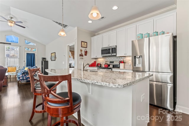 kitchen featuring appliances with stainless steel finishes, decorative light fixtures, a kitchen island with sink, and white cabinets