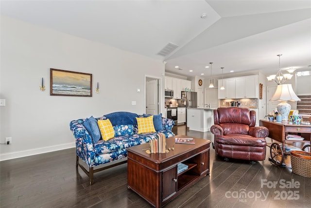 living room featuring dark hardwood / wood-style floors, vaulted ceiling, and a notable chandelier