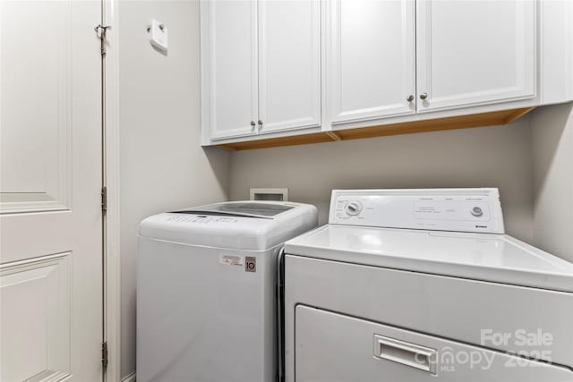 laundry area featuring separate washer and dryer and cabinets