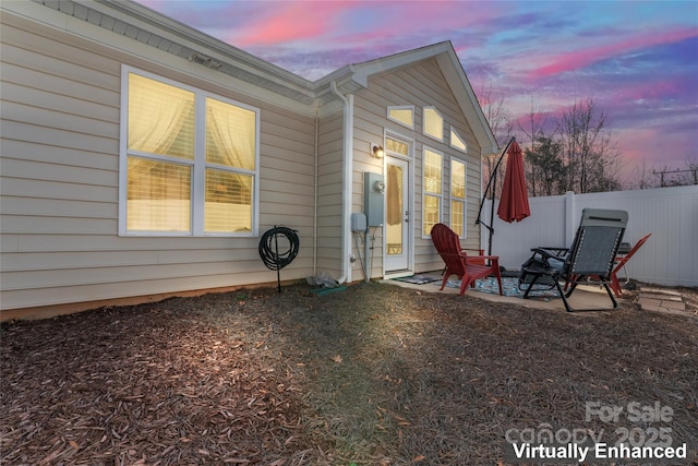 back house at dusk featuring a patio