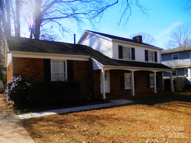 traditional home featuring covered porch, brick siding, and a chimney