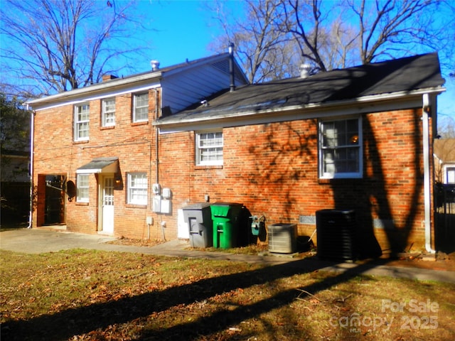 rear view of property with brick siding, a patio area, and central air condition unit