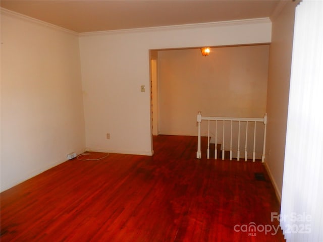 empty room with ornamental molding, dark wood-style flooring, and baseboards