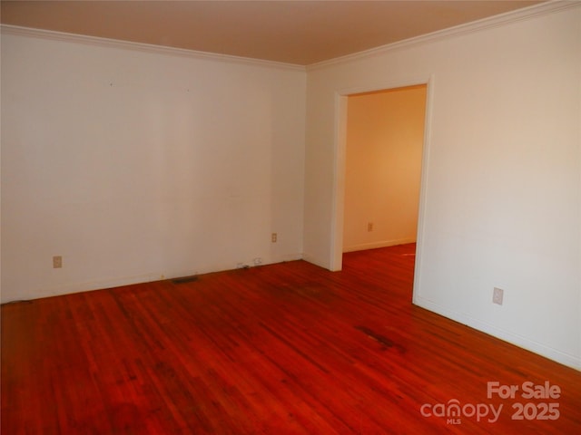 empty room with visible vents, crown molding, baseboards, and wood finished floors