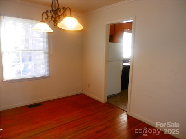 unfurnished dining area with ornamental molding, dark wood-type flooring, plenty of natural light, and visible vents