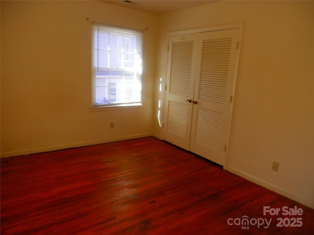 unfurnished bedroom featuring a closet, baseboards, and wood finished floors