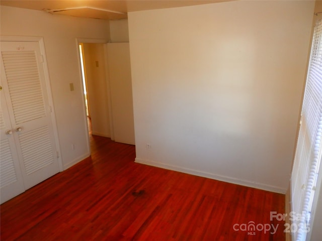 unfurnished bedroom featuring dark wood-style flooring and baseboards