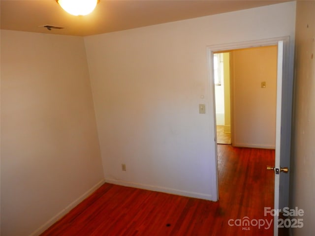 unfurnished room with dark wood finished floors and baseboards