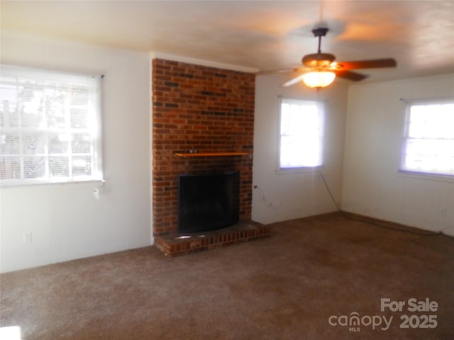 unfurnished living room featuring a brick fireplace, a healthy amount of sunlight, ceiling fan, and carpet flooring