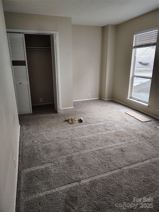 unfurnished bedroom with carpet, a textured ceiling, and a closet