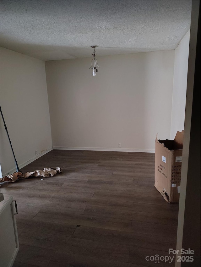 unfurnished room with dark wood-type flooring and a textured ceiling