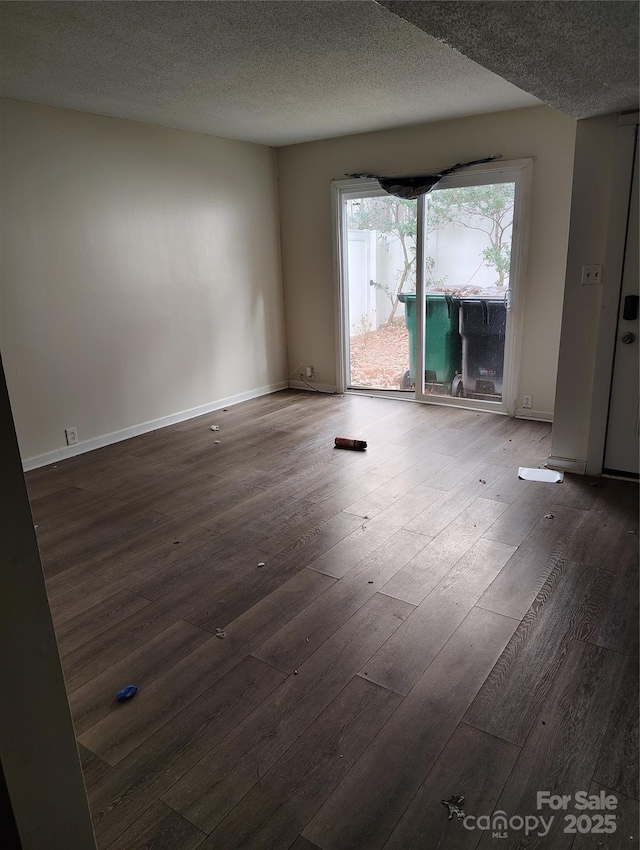 spare room featuring dark hardwood / wood-style floors and a textured ceiling